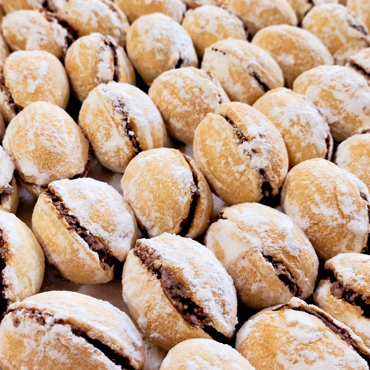 Close-up of powdered-sugar walnut-shaped sandwich biscuits